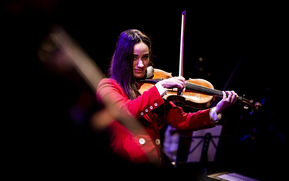 Violinist wearing a red suit at Hear and Now culmination performance, 2019