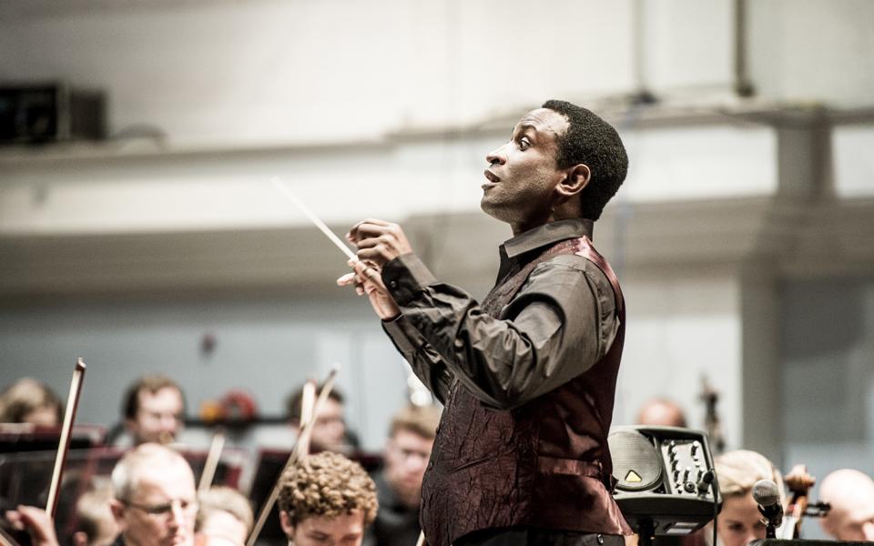 Kwamé Ryan conducting the Philharmonia, wearing a vest