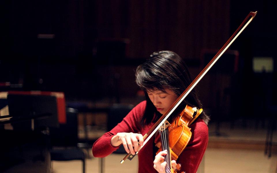 Julia Liang, from the Philharmonia MMSF Instrumental Fellowship Programme plays the violin on stage in rehearsal