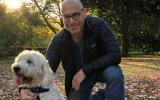 Saul Nathan with his dog kneeling on the ground in the woods