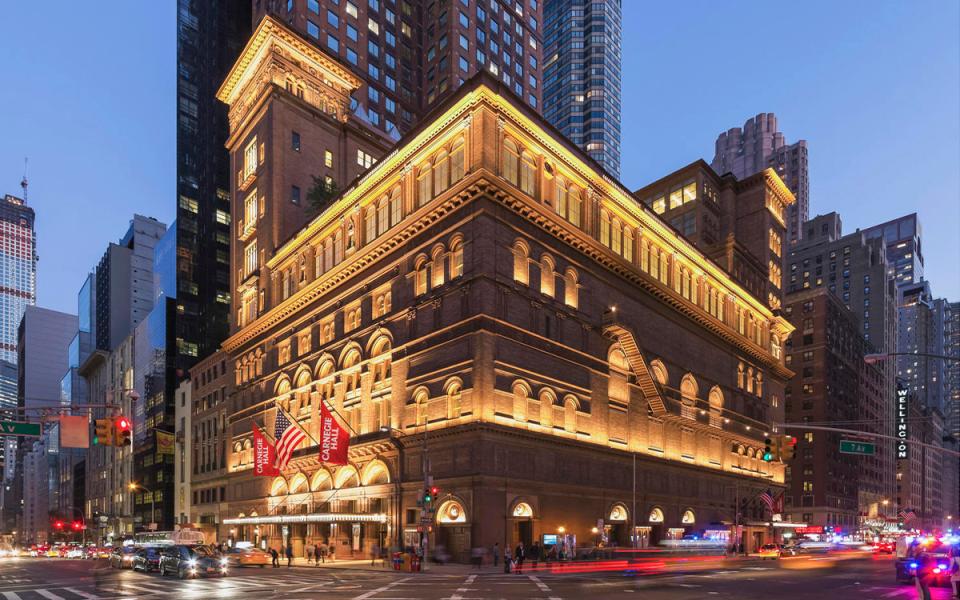 8. Carnegie Hall credit Jeff Goldberg _ Esto Exterior of Carnegie Hall in the evening. The lights are on and there is a blur of flights from vehicles passing by