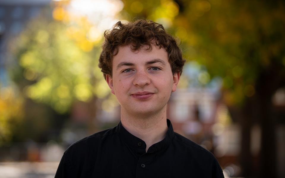 Eddie Mead_Cello Eddie smiling at camera outside Philharmonia office
