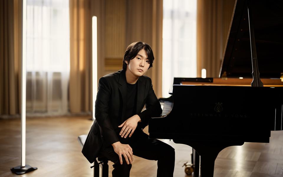 Seong-Jin Cho sits at the keyboard, looking towards the photographer.