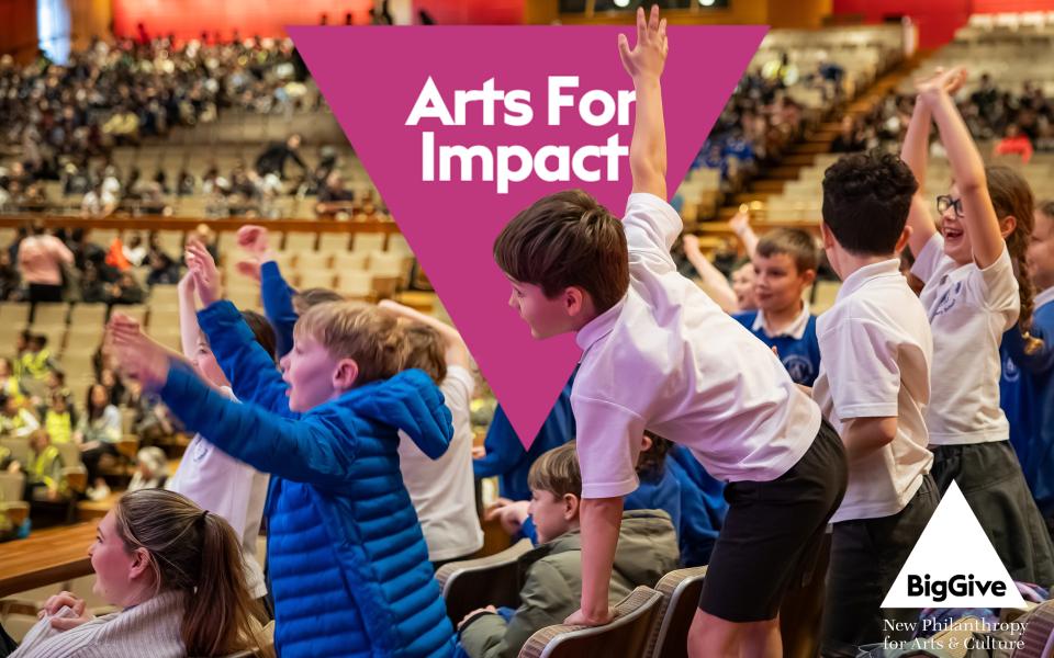 Arts for Impact logo superimposed over children at Orchestra Unwrapped with hands raised.