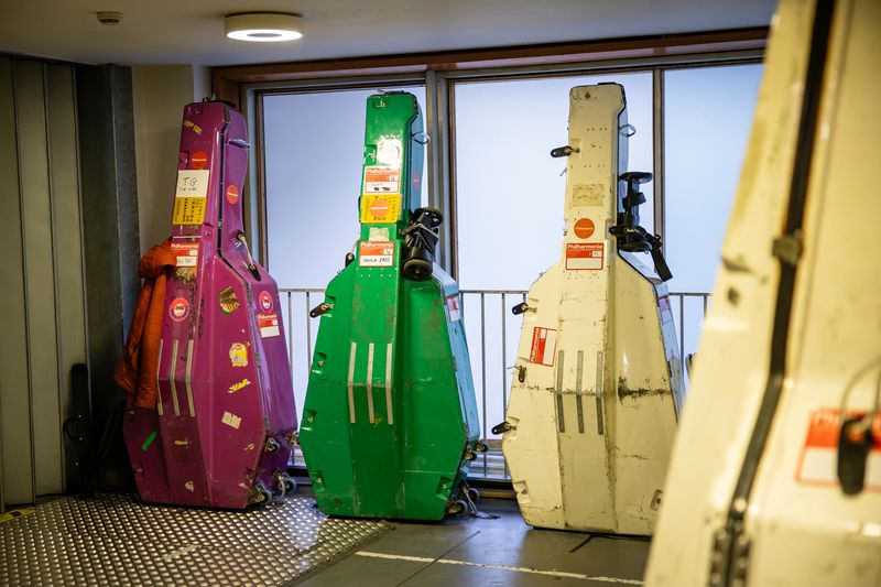 Double bass cases stood upright with Philharmonia stickers on the cases.