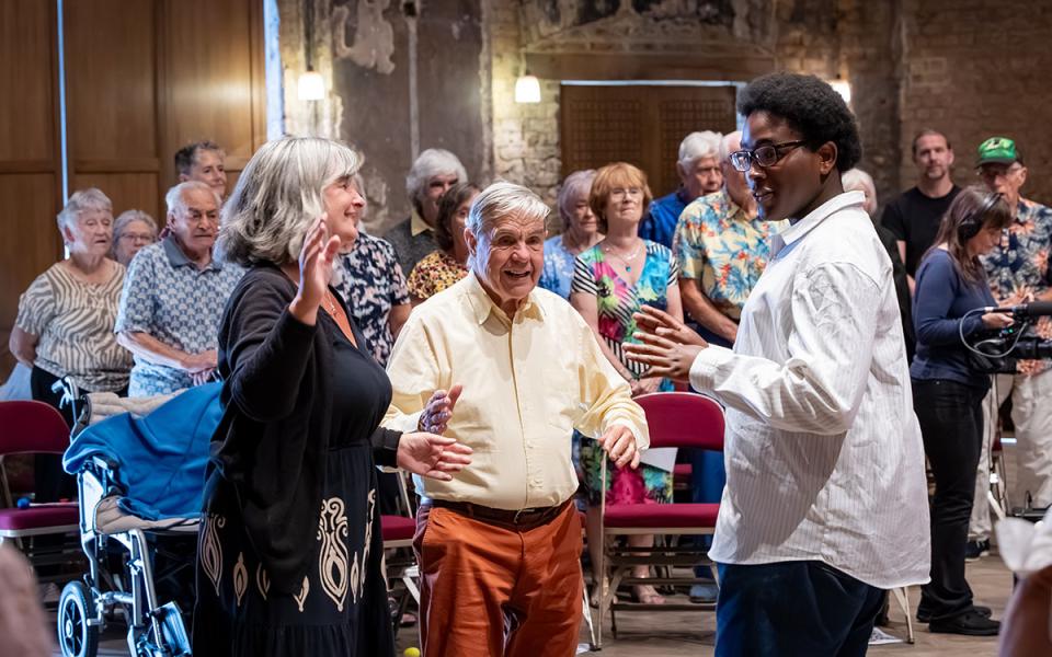 Three adults standing in a group, smiling and dancing