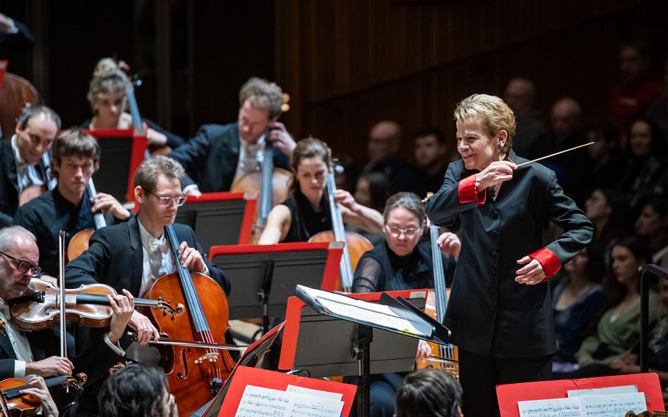 Marin Alsop conducing the Philharmonia with the cellists in the background