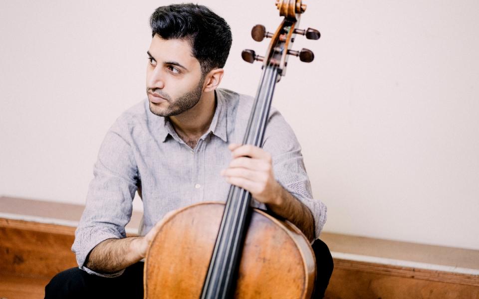 Kian Soltani with his cello, looking over his shoulder to his right