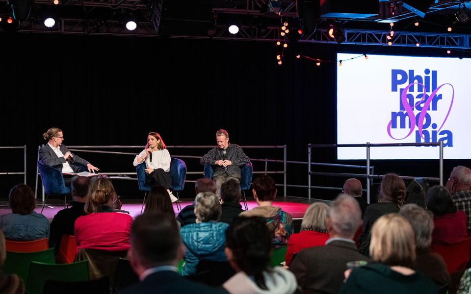Three people sat on stage giving a talk