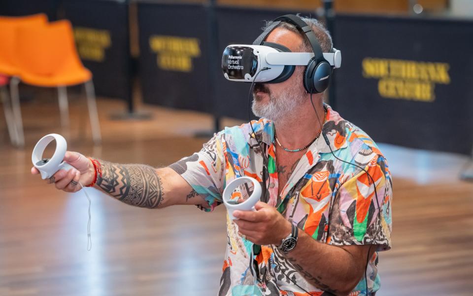 Man using Philharmonia Virtual Orchestra VR product, holding two handsets in front of him with headset