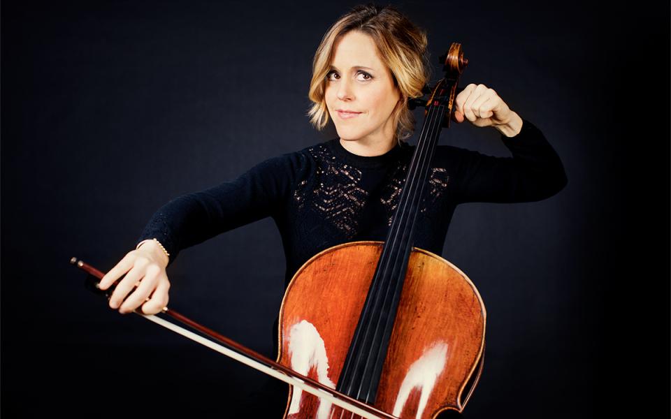 Sol Gabetta against a black background playing her cello