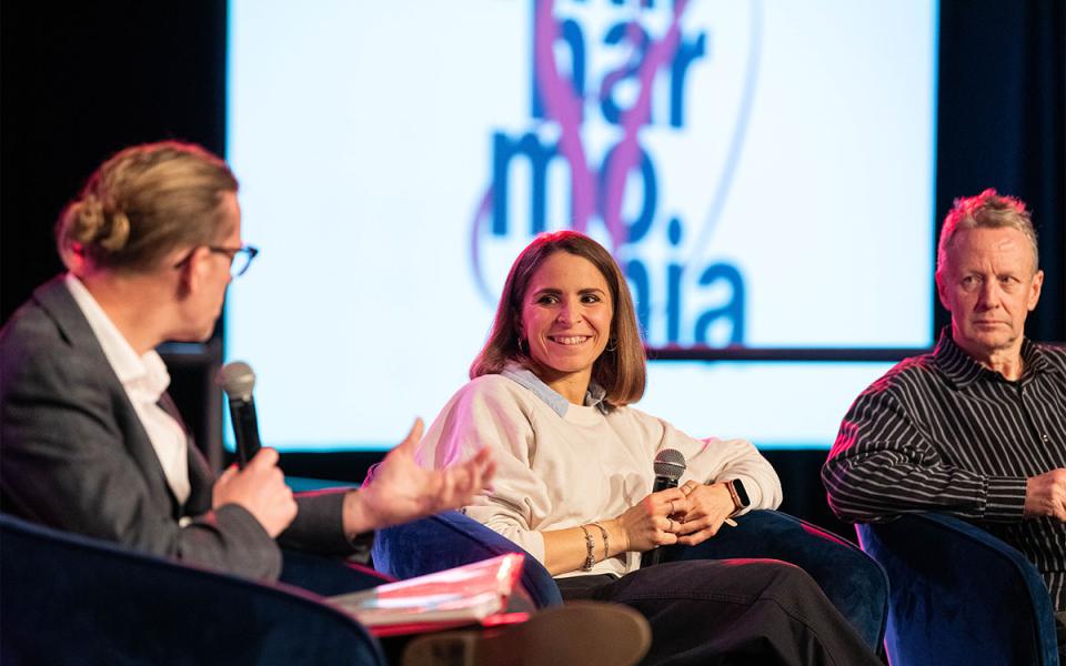 A philharmonia debate taking place with the 80th logo on a screen in the background.