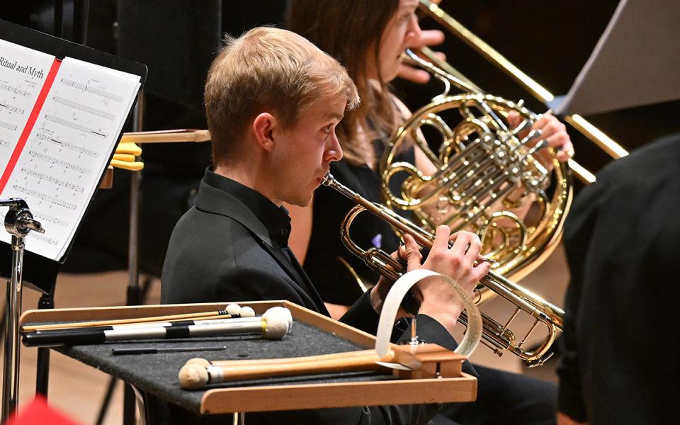 A side profile of a male PIF playing trumpet